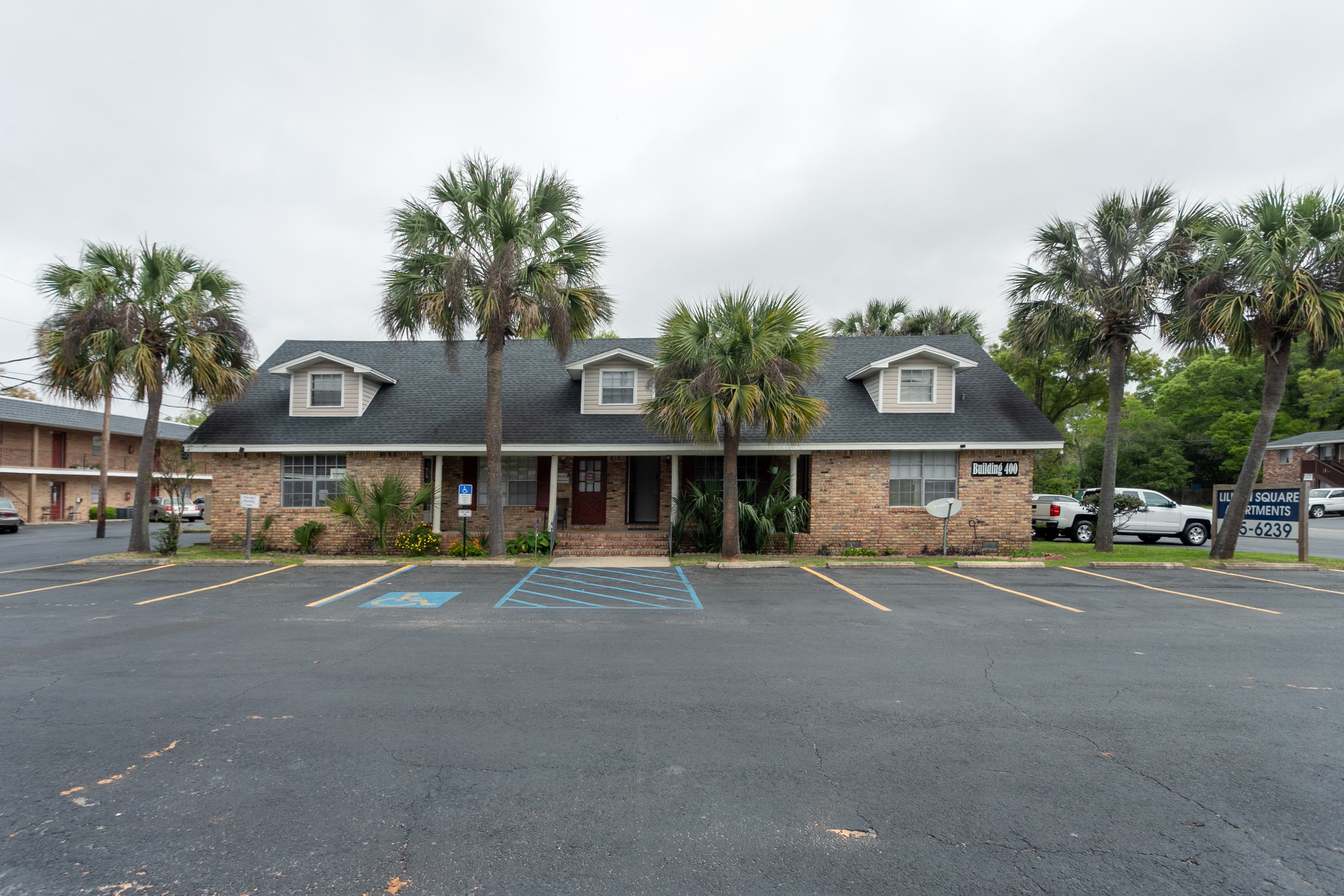 A parking lot with a building and palm trees in the background.